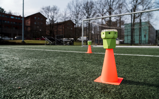 Izzy Hunter on a turf field setting out orange sensor cones for a sprint drill