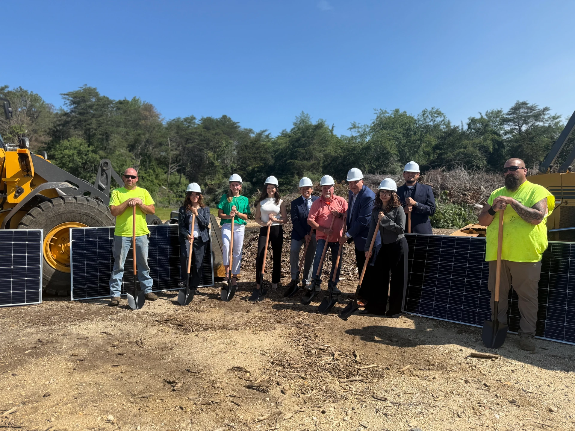 Solar panels installed on a fenced industrial brownfield site with grass and tree line in the background